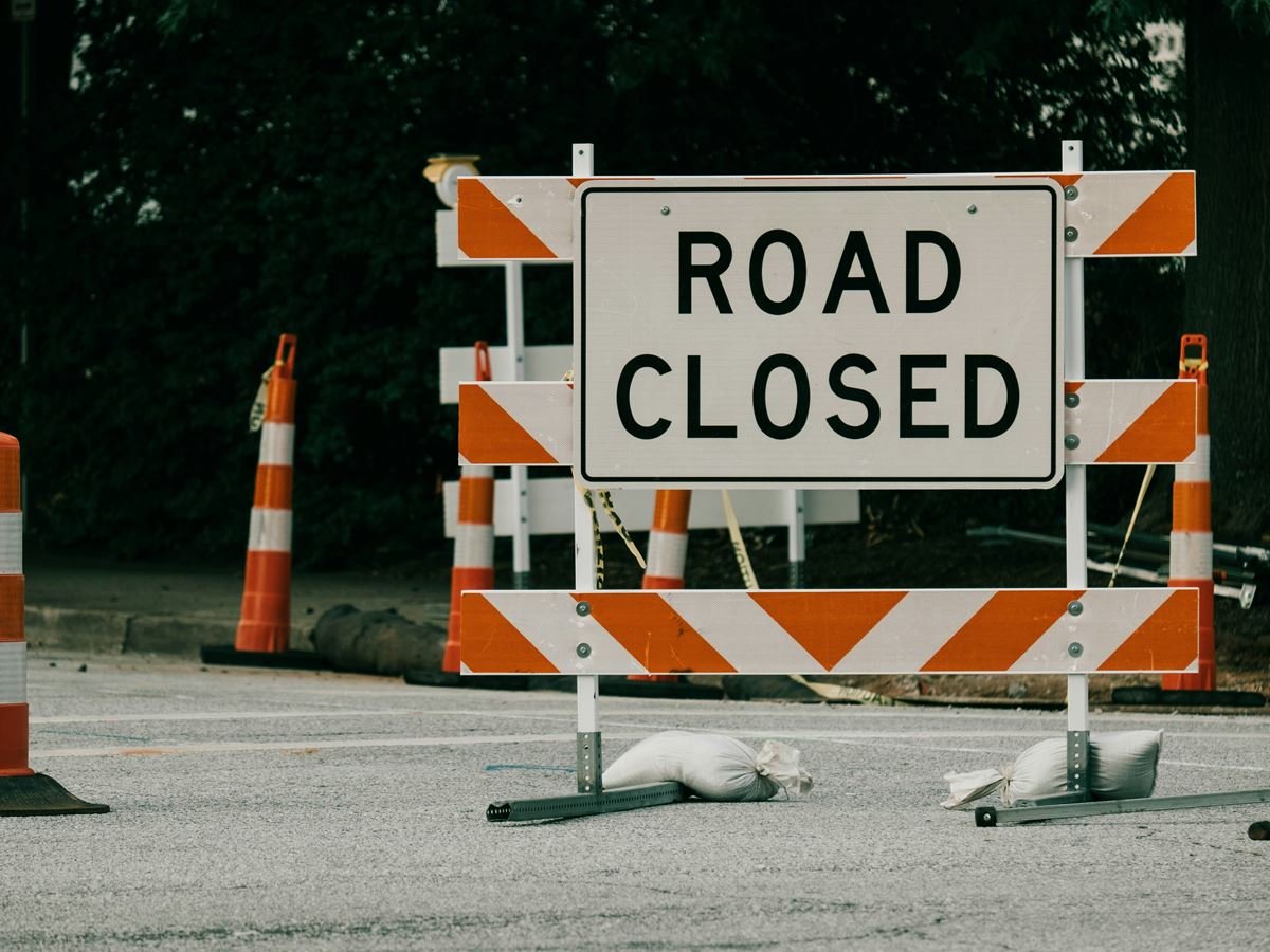 Road Closed barricade with orange and white traffic drums
