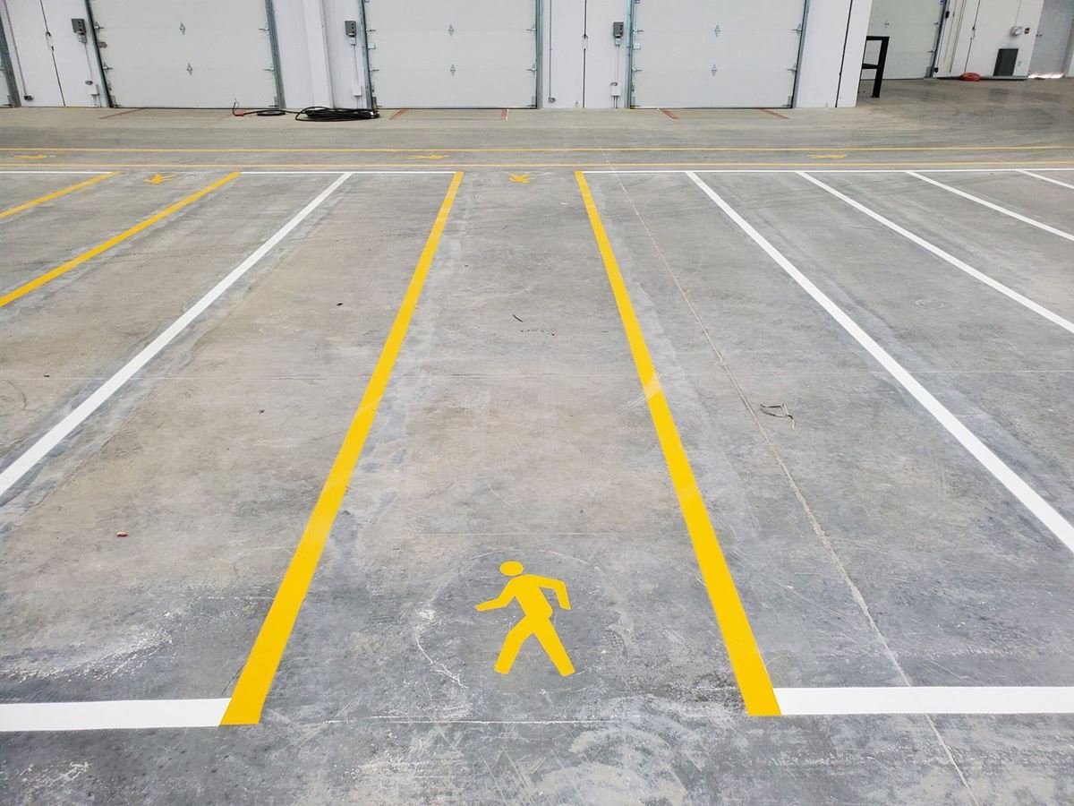 Warehouse loading area with yellow pedestrian walkway lines and a walking-person symbol